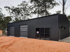 a black building with two garage doors on the front and one door open to let in light