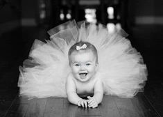 a baby is laying on the floor wearing a tutu and smiling at the camera