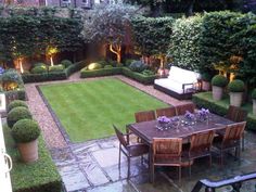 an outdoor dining area is lit up with lights and greenery in the back yard