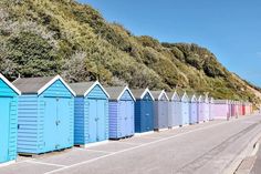 there are many beach huts lined up along the side of the road