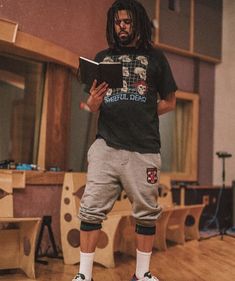 a man standing on top of a wooden floor in front of a table holding a book