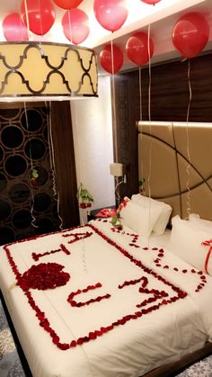 a bed with red and white decorations on top of it in a room that has balloons hanging from the ceiling