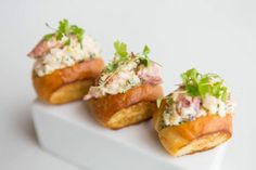 three appetizers are sitting on a white plate with green garnishes