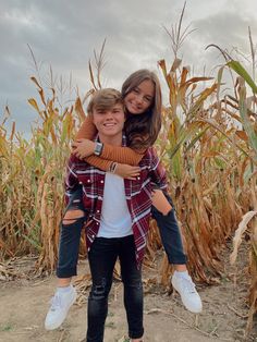 two girls hugging each other in front of a corn field