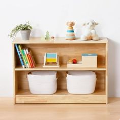 a wooden shelf with two white baskets on top of it next to a stuffed animal and bookshelf