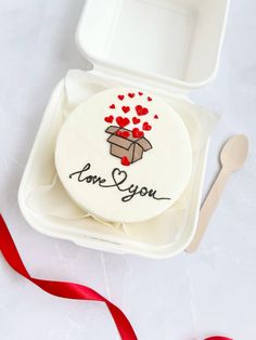 a cake in a box with the words i love you on it and red hearts