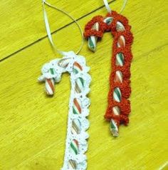 two christmas ornaments are sitting on a wooden table, one is decorated with candy canes and the other has an ornament