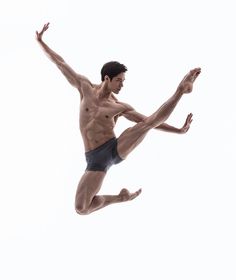 a shirtless man jumping in the air with his legs spread out and one leg bent