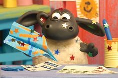 a cartoon sheep holding a pen and paper in front of a cup with stars on it