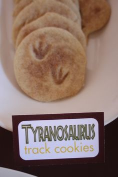 there is a plate with cookies on it and a sign that says tyanosaurius track cookies