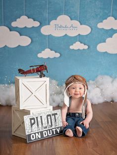 a baby is sitting on the floor with a propellor and sign in front of him