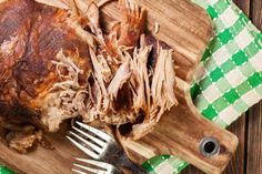 a piece of meat sitting on top of a wooden cutting board next to a fork