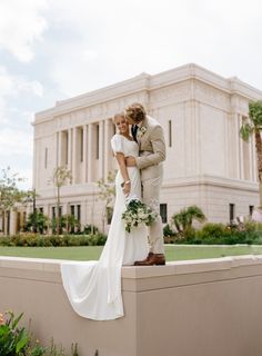 a bride and groom pose for a photo in front of the stately building