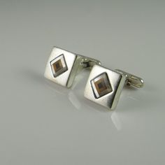 A custom made pair of semi precious gem inlay and solid sterling silver men's cufflinks circa 1980. This quality hand made pair of fine sterling silver cufflinks are set with fine inlay of tigers eye, mother of pearl and onyx. The design is eye catching and timeless. Each cufflink has been made by hand so there is some slight variation between one inlaid cuff link to the other. These unique cufflinks are a classic size measuring 9/16" square (14mm). Together they weigh 12.41 grams. There are som Antique Cufflinks, Mens Cuff, White Onyx, Semi Precious Gems, Vintage Cufflinks, Silver Cufflinks, Cufflinks Men, Sterling Silver Mens, Precious Gems