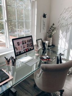 a glass desk with a computer on top of it next to a chair and window