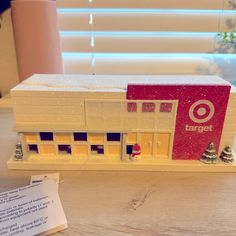 a close up of a small toy building on a table with a note in front of it