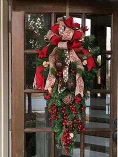 a christmas wreath on the front door of a house with bells and holly berries hanging from it