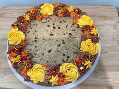 a cake decorated with yellow flowers and chocolate chips on a wooden table next to utensils