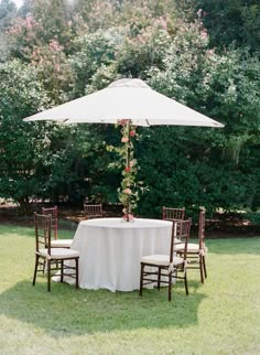 a table with chairs and an umbrella in the grass