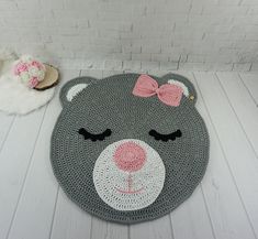 a crocheted teddy bear rug with a pink bow on it's head