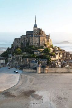 an old castle sits on top of a hill near the ocean and beach in france