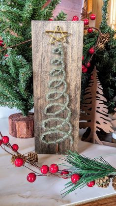 a wooden sign sitting on top of a table next to christmas decorations and pine cones