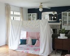 a canopy bed in a living room next to a couch and table with pillows on it