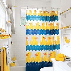 a bathroom decorated in yellow and blue with rubber ducks on the shower curtain next to the tub