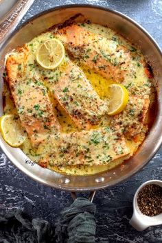 a pan filled with fish covered in lemons and parsley next to some spices