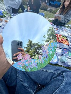 a person holding up a phone in front of a mirror that has flowers on it