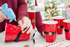 a person pouring something into red cups with candy canes on the table next to them