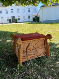 a wooden bench sitting on top of a lush green field next to a white building