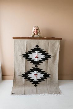 a woman standing behind a large black and white blanket on top of a wooden table