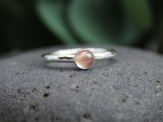 Handmade Sterling Silver Red & Peach Oregon Sunstone Stacking Ring  Sunstone is said to be the gemstone of leadership, and to inspire good will...who knew?  It is also the official gemstone of the state of Oregon and you can literally pick gemstone up right off the ground out in South Central Oregon, near Plush, Oregon.  Here are the details:   * This ring is made with a 5mm genuine Oregon sunstone, and will be a pale peachy pink or multi-colored.  Need a plain stacker, too? https://www.etsy.com/listing/976004217/ * This ring is made to order, so please allow about a week for completion. Your ring will be packaged in a sturdy box inside a bubble mailer and shipped via USPS First Class Mail. An upgrade to USPS Priority Mail is available for an additional fee. As with all of my items, everyt Peach Gemstone Jewelry, Round Peach Gemstone Jewelry, Peach Round Gemstone Jewelry, Peach Ring Jewelry Gift, Peach Natural Stones Jewelry Gift, Peach Jewelry With Natural Stones For Gift, Student Care Package, Gemstone Stacking Ring, Plain Silver Rings