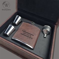 a leather flask and two shot glasses in a box with the word arther written on it