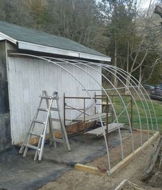 a small white building with a metal roof and ladders on the side of it