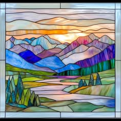 a stained glass window with mountains and trees in the background, as well as sunset