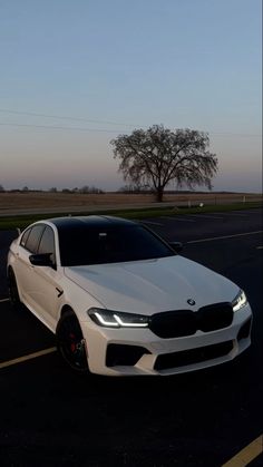 a white car parked in a parking lot next to an empty road with trees on the other side