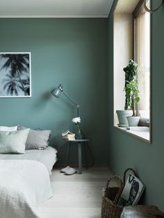 an image of a bedroom with green walls and white bedding in the foreground