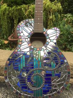 a stained glass guitar sitting on the ground