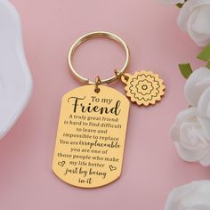 a gold keychain with the words to my friend on it next to flowers