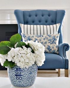 a blue and white flower pot sitting on top of a table next to a chair