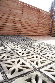 an outdoor area with wooden fence and decorative tiles on the ground, in front of a building