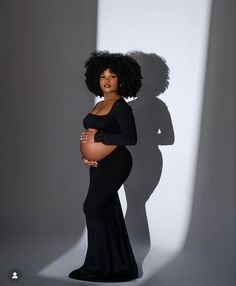 a pregnant woman standing in front of a shadow