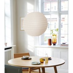 a table with plates and cups on it in front of a large round light fixture