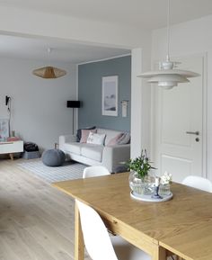 a living room filled with furniture and a wooden dining table in front of a white couch