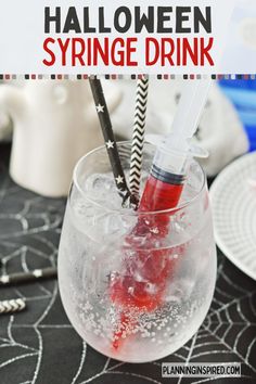 a glass filled with red liquid and two black straws in it on top of a table