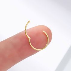 a person's finger with a small gold ring on top of their thumb,