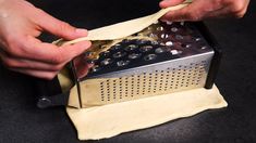 a person is peeling something off of a piece of paper with a grater in their hand