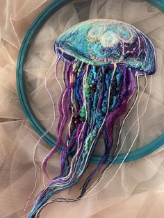 a jellyfish with multicolored hair is hanging from a hoop